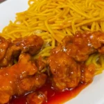 Close-up of crispy hot orange chicken from Panda Express, coated in a flavorful orange glaze with a hint of spice